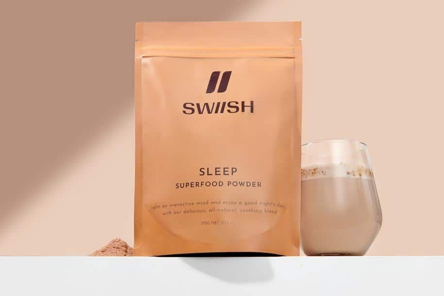 SWIISH Sleep Superfood Powder pouch styled beside a pile of the powder and a mixed up hot sleep drink in a glass