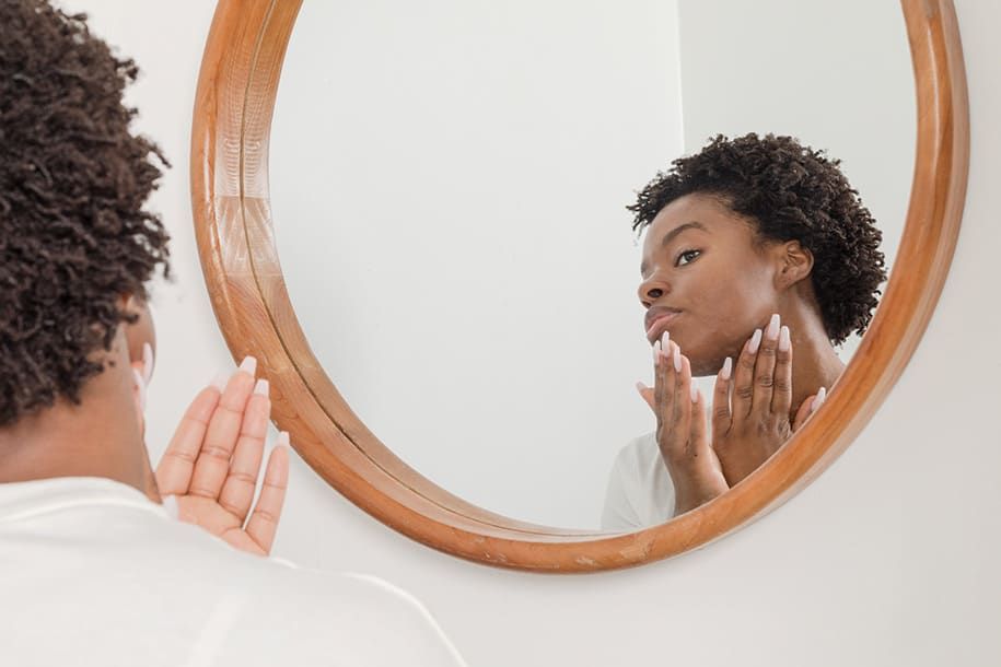 Woman looking in mirror at her problem skin